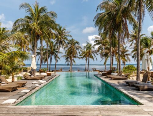 Indonesia resort swimming pool with lungers, beach view