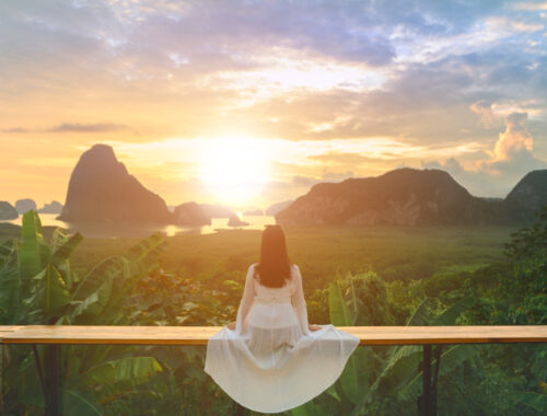 woman in white dress looking at sunrise and mountains