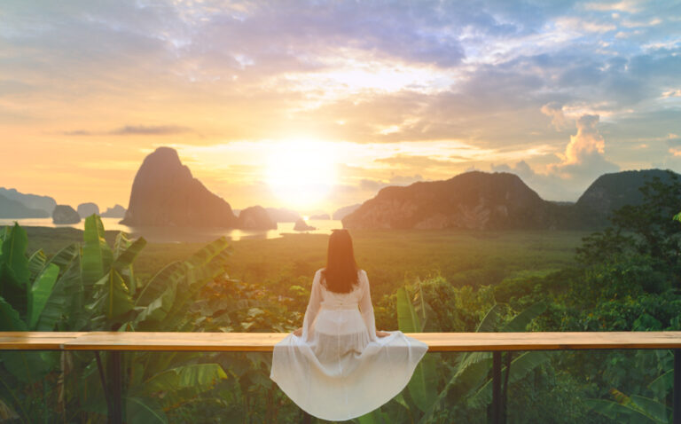 woman in white dress looking at sunrise and mountains