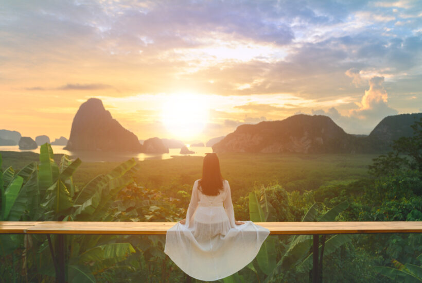 woman in white dress looking at sunrise and mountains