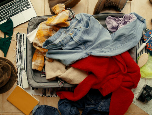 Suitcase on floor with clothes piled on top
