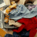 Suitcase on floor with clothes piled on top