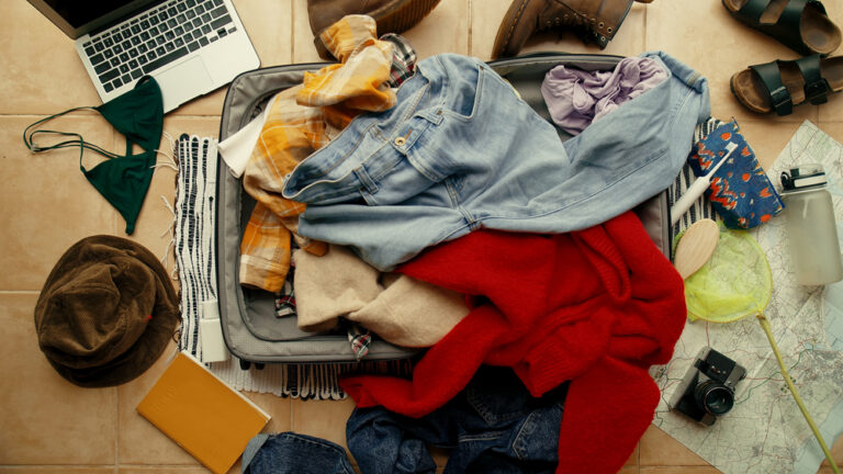 Suitcase on floor with clothes piled on top
