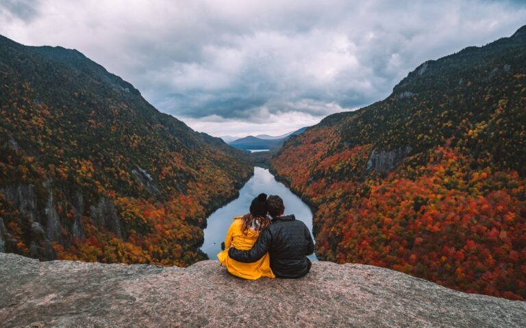 Couple holding each other on top of mountain cliff in Autumn