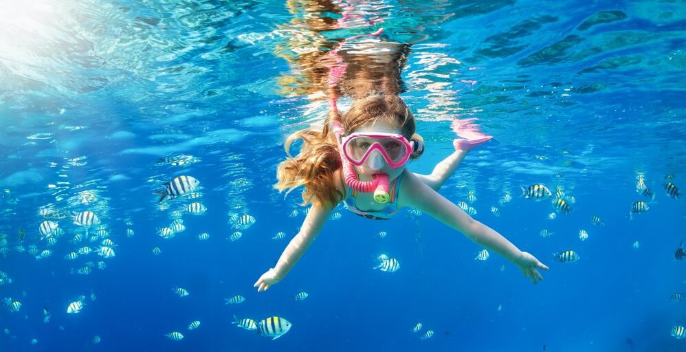 girl snorkeling tropical beach with fish