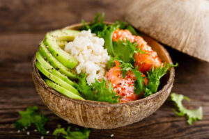 Hawaiian poke coconut bowl with grilled salmon fish, rice and avocado.