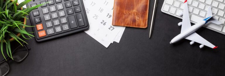 calculator, passport, keyboard, model airplane on desk.