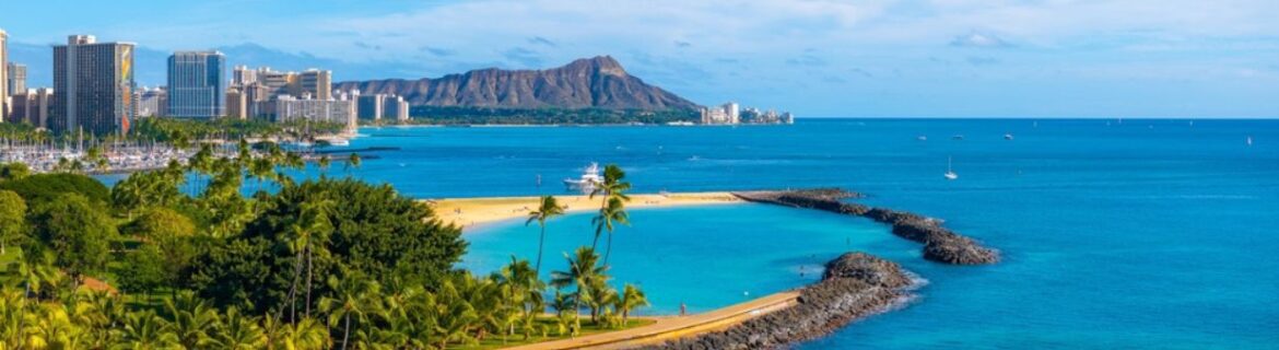 Aerial view of Oahu's Ala Moana Beach park, Waikiki and Diamond Head mountain in distance. blue ocean and palm trees.