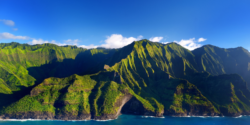 Jagged emerald green mountain cliffs, deep blue sky.