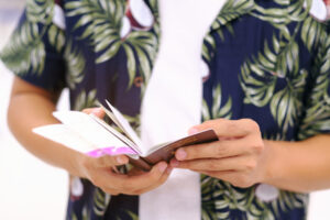 Body shot of a man in hawaiian shirt holding a passport.
