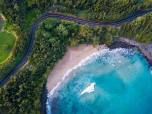 Which Is the Least Crowded Hawaiian Island? (2026 Guide to a Peaceful Hawaii Vacation) Aerial view of the sandy beach and curved asphalt road on the west coast of Maui. Hawaii.