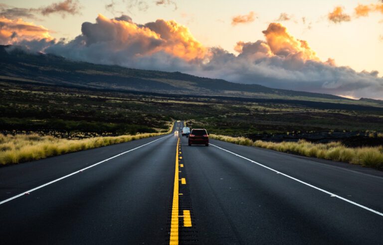 Driving on long road with mountain slope in background.