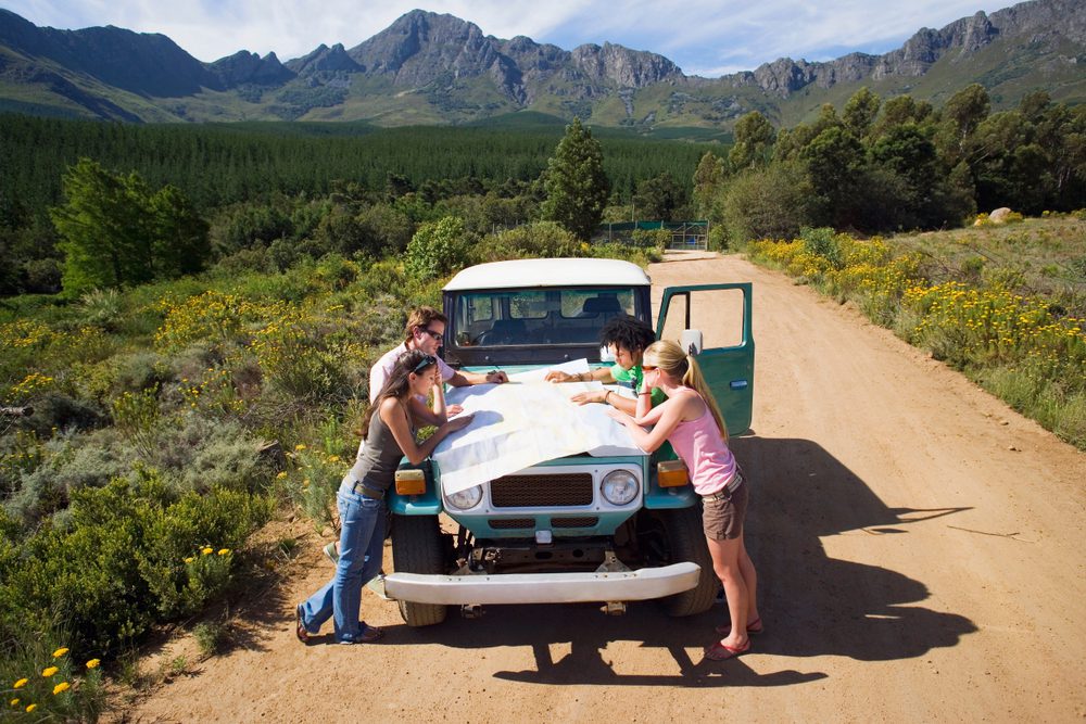 Do You Need a Rental Car in Hawaii? Island-by-Island Guide group,of,young,adults,on,road,trip,reading,map,by