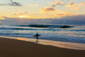 Which Is the Least Crowded Hawaiian Island? (2026 Guide to a Peaceful Hawaii Vacation) beach at the North Shore of Oahu, Hawaii, with an unrecognizable surfer.