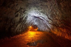 Lava tube cave, lit up by yellow orange light.