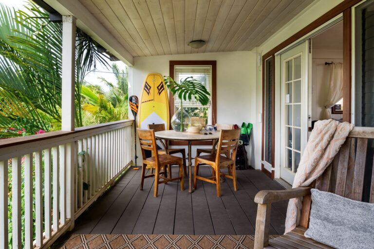 Paia Inn large lanai with chairs and table, surfboard leaning on wall.