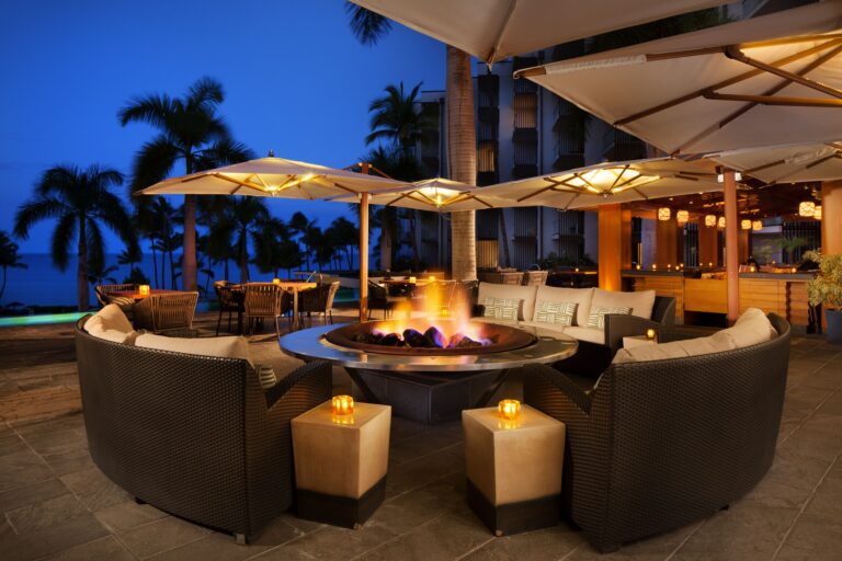 Pooside bar at night with chairs around firepit.