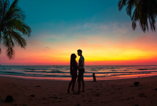 Silhouette of couple on tropical beach at sunset