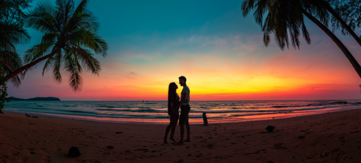 Silhouette of couple on tropical beach at sunset