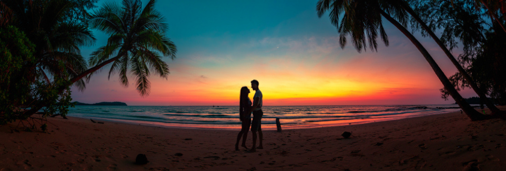 Silhouette of couple on tropical beach at sunset