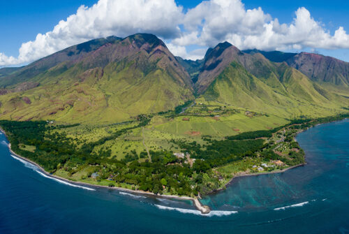 High aerial Shot of Maui. Green mountains, blue ocean on both sides.